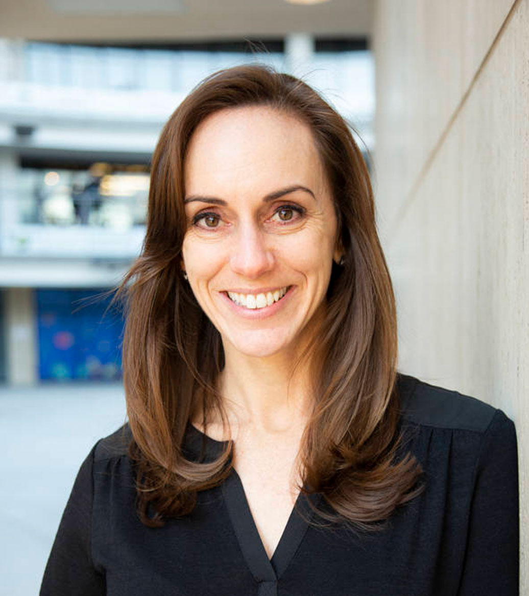 Woman smiling with long brown hair wearing a black shirt